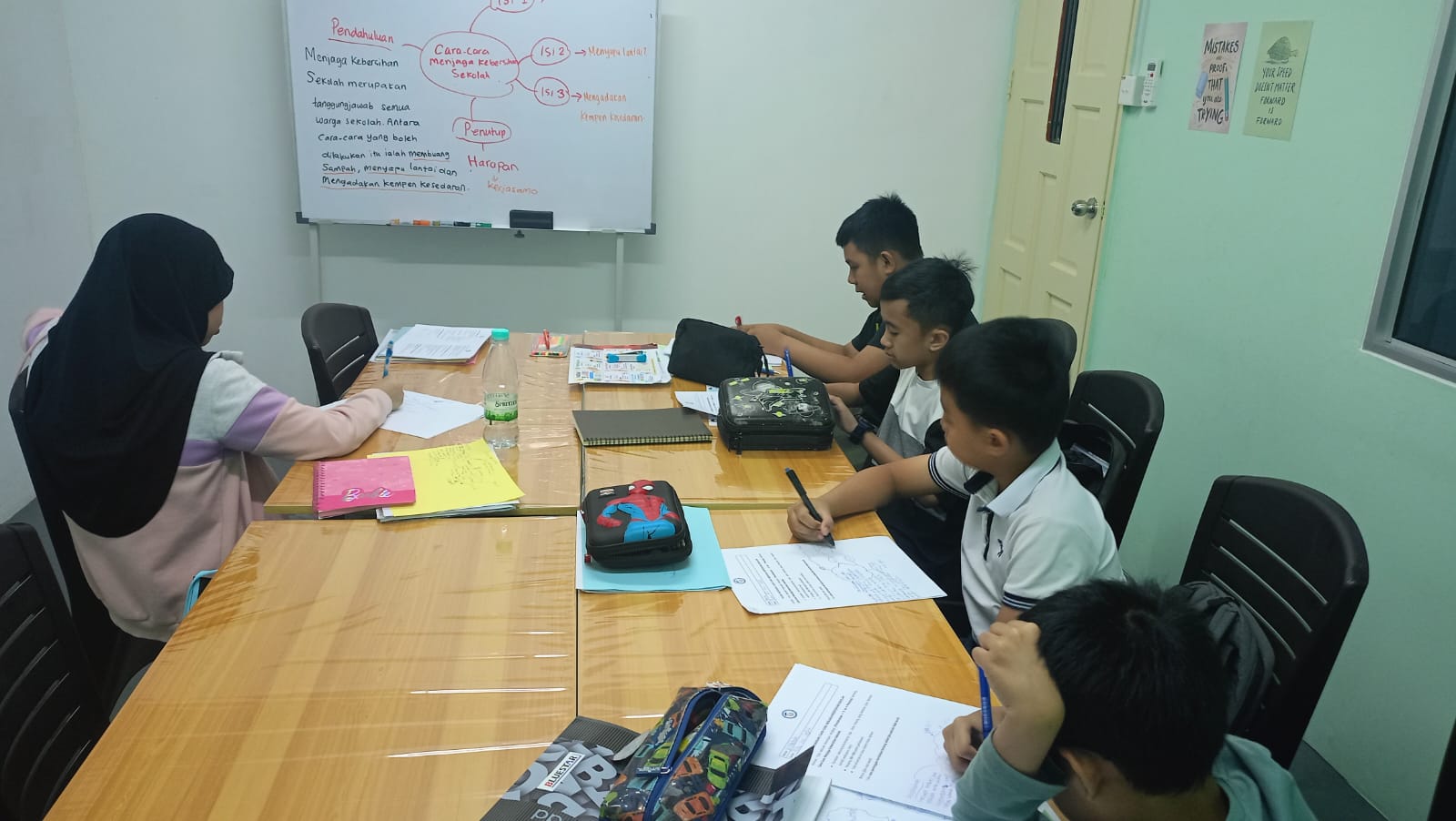 AFTC students practising writing around a classroom table